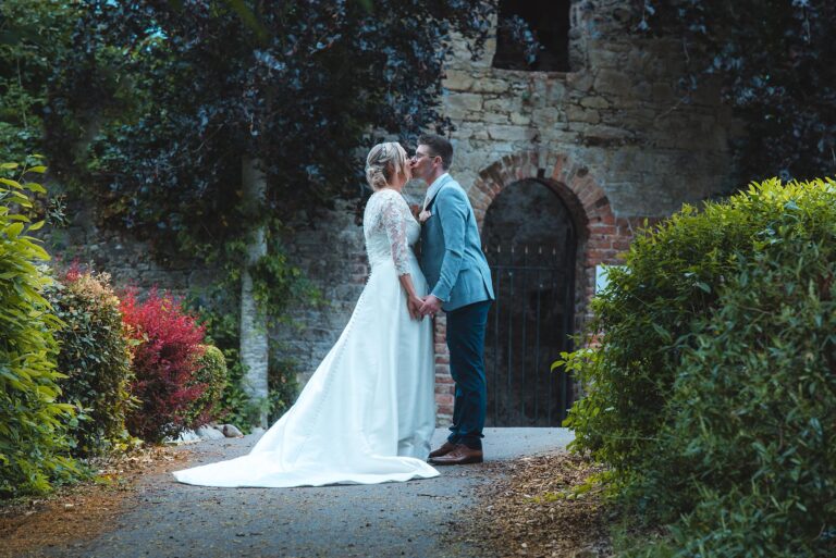 Happy bride and groom sharing a kiss during sunset ceremony.