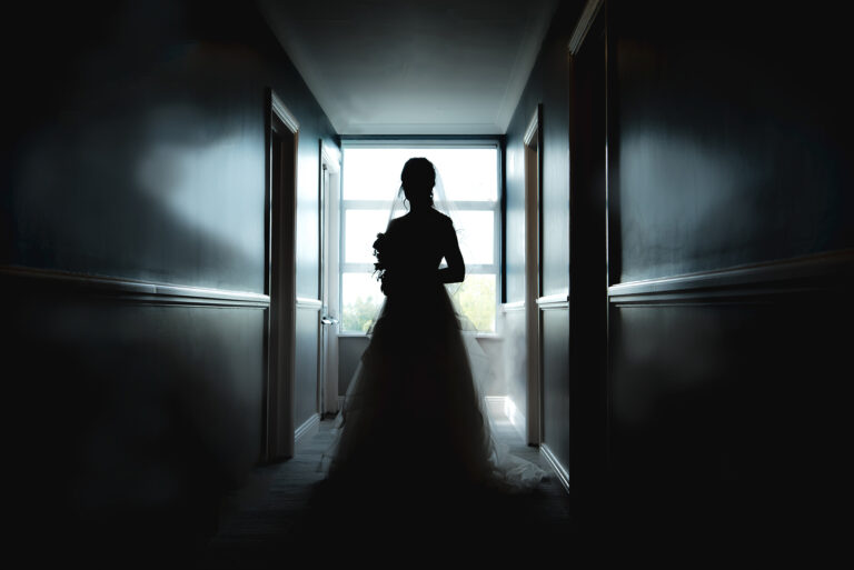 Dramatic silhouette of the bride with her flowing veil, creating a captivating outline.